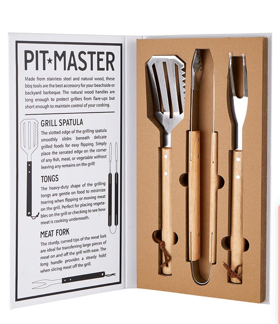 A set of barbecue tools including a grill spatula, tongs, and a meat fork, presented in a book-style package with the 'Pit + Master' brand visible.