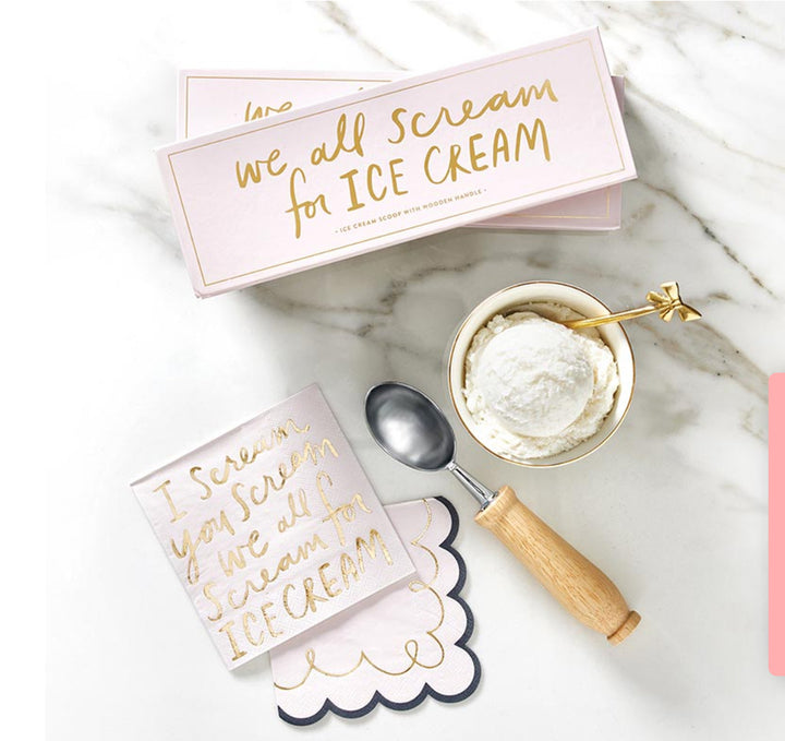 A set of ice cream themed kitchen accessories including a wooden ice cream scoop, a melting ice cube tray, and decorative ice cream scoops on a marble countertop. Packaging in the background reads 'We all scream for ice cream'.